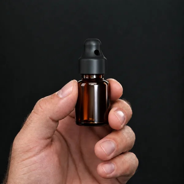 Hand holding a 10 ml amber glass bottle with a SN*F Small sniffer cap