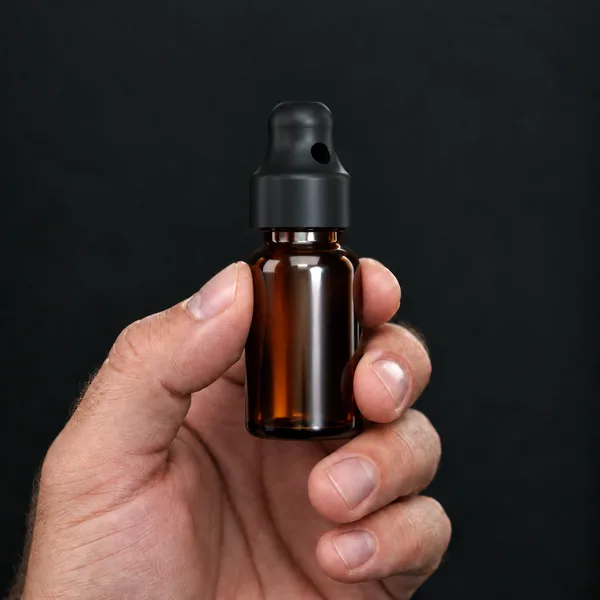Hand holding a 15 ml amber glass bottle with a SN*F Small sniffer cap