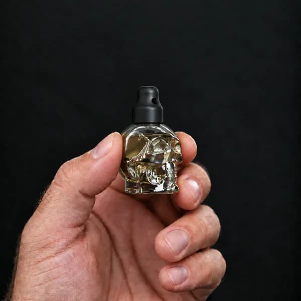 Hand holding a 15 ml skull, clear bottle with a SN*F X-Small sniffer cap