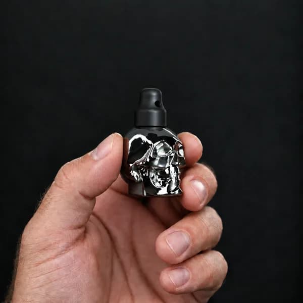 Hand holding a 15 ml skull, silver bottle with a SN*F X-Small sniffer cap