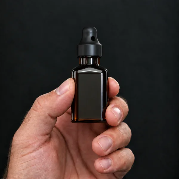 Hand holding a 24 ml square, amber bottle with a SN*F Large sniffer cap