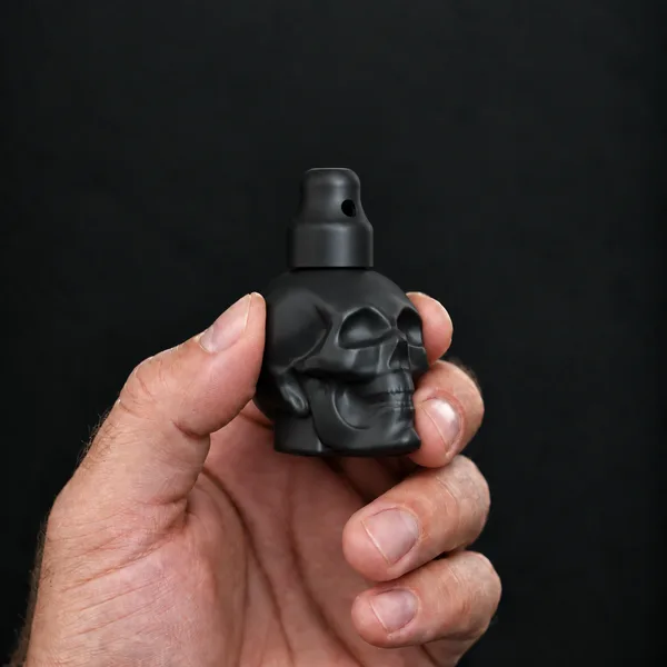 Hand holding a 24 ml skull, black bottle with a SN*F X-Small sniffer cap