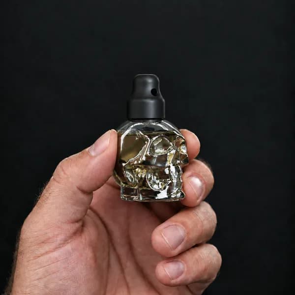 Hand holding a 24 ml skull, clear bottle with a SN*F X-Small sniffer cap