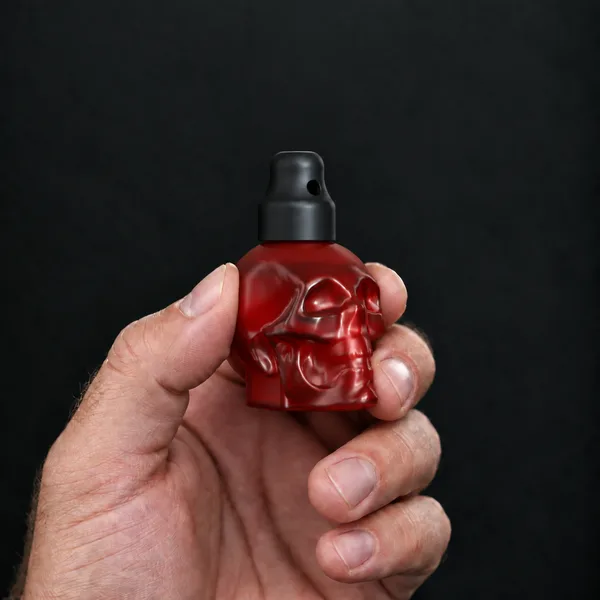 Hand holding a 24 ml skull, red bottle with a SN*F X-Small sniffer cap