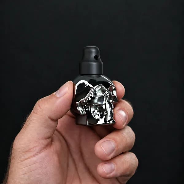 Hand holding a 24 ml skull, silver bottle with a SN*F X-Small sniffer cap