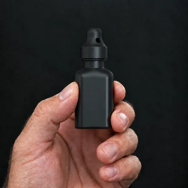 Hand holding a 24 ml square, black bottle with a SN*F Large sniffer cap
